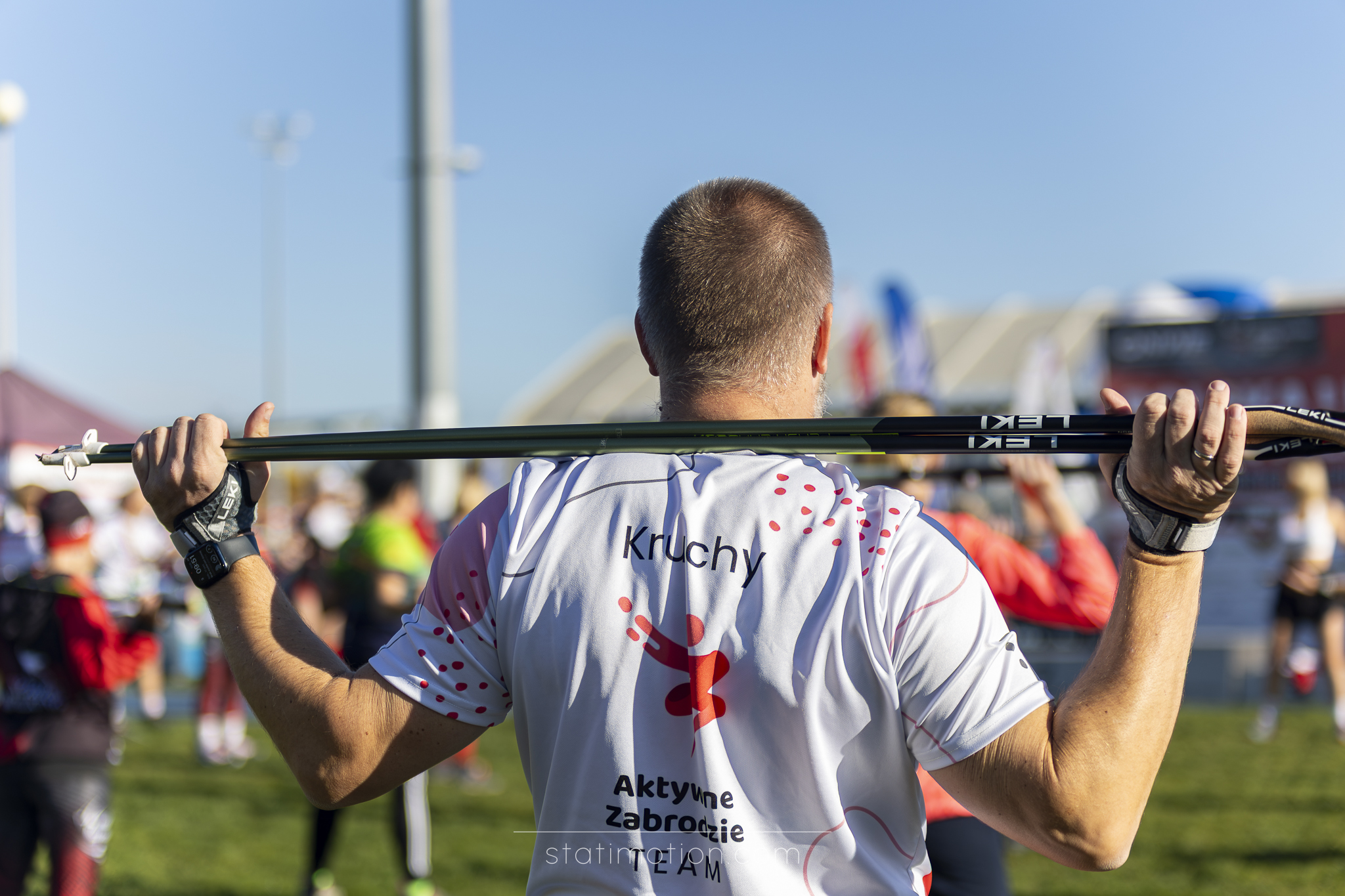 Karol Kruchy wykonuje ćwiczenie rozgrzewkowe z kijami nordic walking